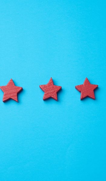 Five red stars and a hand on a blue background. Evaluation of the quality of services and goods